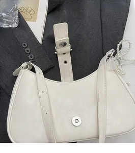 Detailed macro view of the metal magnetic clasp on white litchi pattern leather handbag