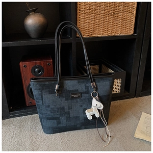 Detail of grey vintage bucket bag with denim texture and white horse leather charm