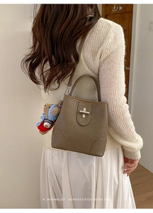 Detail of a dark brown pebble leather bucket bag with teddy bear charm on model