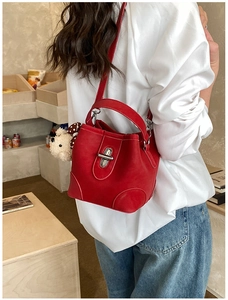 Detail of red leather bucket bag with silver twist lock and cute white bear plush charm