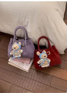 Detail view of purple and deep red leather bucket bags with cute bear charm and buckle