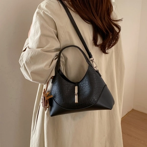 Detail view of black hobo bag with textured leather, silver clasp, and tassel accent