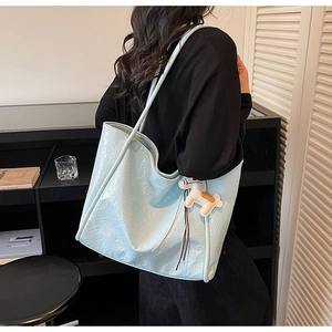 Detail view of light blue tote bag with ruched texture and a white horse charm