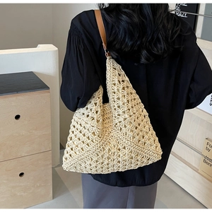 Detail of hollow woven beach tote bag with brown leather straps and geometric pattern