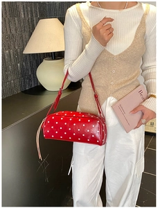 Detail of red polka dot cylinder bag with fringe zipper and adjustable strap