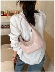 Detail of light pink crescent bag with geometric stitching and woven rope tassel on strap