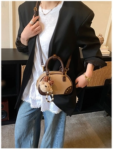 Detail of a two-tone PU leather crossbody bag with teddy bear charm on model outfit