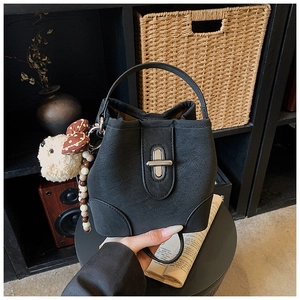 Black leather bucket bag with silver clasp and white plush bear charm detail
