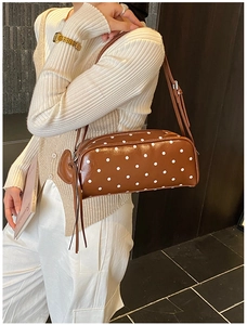 Detailed side view of the brown polka dot shoulder bag with stylish tassel and slim strap