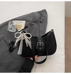 Detail of black crescent shoulder bag with silver buckle and pearl bow ribbon charm