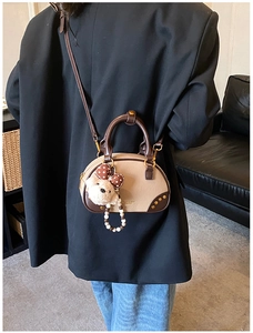 Detail of trendy two-tone pillow bag with bear charm and beaded chain on a model