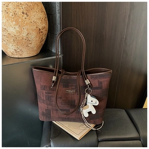 Detail of vintage canvas bucket bag with leather straps and white horse charm accessory
