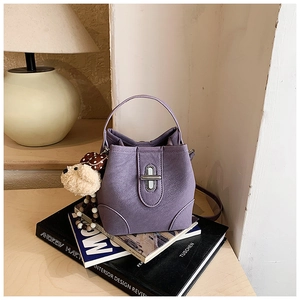 Detail of purple bucket bag with silver twist lock and cute plush puppy charm