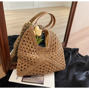 Detail of hollow woven beach tote with brown leather handles and interior lining