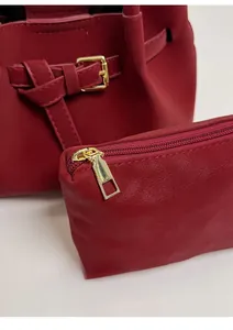 Detailed close-up of red leather bucket bag with golden buckle and zipper pouch