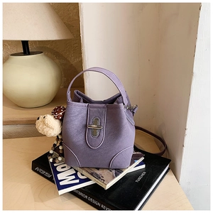 Detail of purple bucket bag with lychee grain texture and a plush charm on books