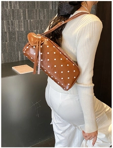 Detail of dark brown polka dot underarm bag with unique heart-shaped leather patch