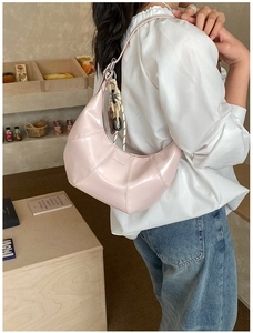 Detail of light pink crescent bag with shiny patent leather and brand logo engraving