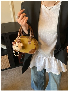 Close-up of stylish mustard yellow and brown pillow bag with cute plush bear charm detail