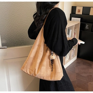 Detail of minimalist beige shoulder bag featuring a coffee cup charm and subtle pattern