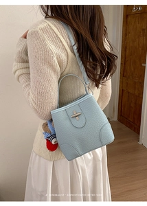 Detail of light blue ostrich texture bucket bag with silver lock and a cute bear charm
