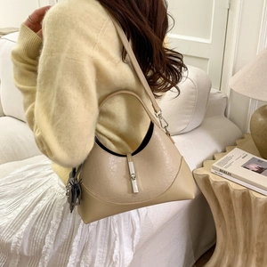 Detail of cream hobo bag with crocodile texture and tassel in a lifestyle setting