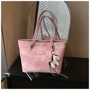 Detail of pink plaid tote bag with stylish horse pendant and metallic brand plaque