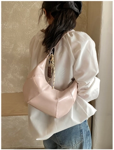 Detail of light pink crescent croissant bag featuring chocolate charm and woven strap