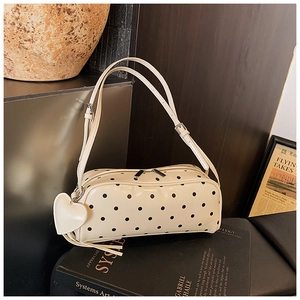 Detailed view of the beige polka dot bag showing its dual zipper and heart-shaped charm