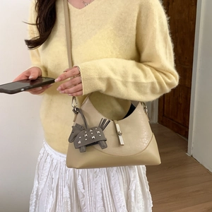 Detail of a beige moon-shaped hobo bag with a stylish horse charm and adjustable strap