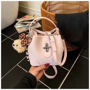 Detail of pink PU leather bucket bag featuring silver turn-lock and brown bear charm