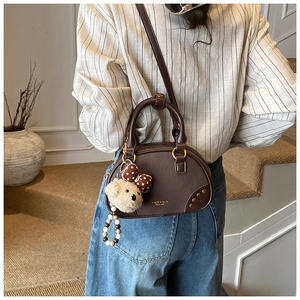 Brown PU pillow bag detail featuring a plush bear charm and metallic rivet accents