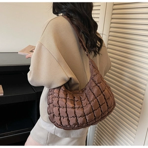 Detail of a dark brown quilted crossbody bag featuring a soft puffy cloud-like texture