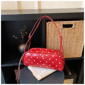 Detailed view of red retro polka dot shoulder bag with dual slim straps on a stool