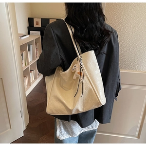 Macro detail of cream shoulder bag featuring wrinkled texture and small horse charm