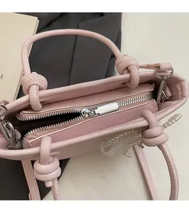 Détail du sac seau rose avec fermeture éclair argentée et poignée nouée à chaîne perlée