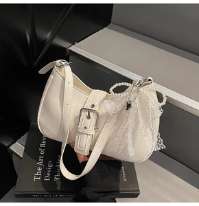 Close-up of cream white underarm bag with silver buckle and pearl lace bow detail