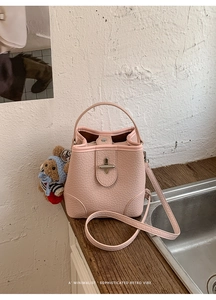 Close-up of pink crocodile texture bucket bag with silver twist lock and bear charm