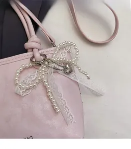 Détail du sac seau en cuir rose avec breloques en perles, dentelle et pendentif cœur argenté