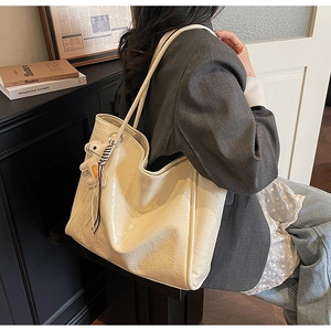 Detail of large cream tote bag with wrinkled texture and cute bear pendant on the shoulder