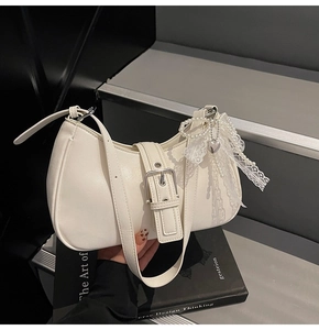Detail of beige leather hobo bag with pearl lace heart charm and elegant buckle strap