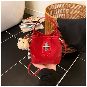 Detail of red velvet bucket bag with silver twist lock and cute teddy bear charm