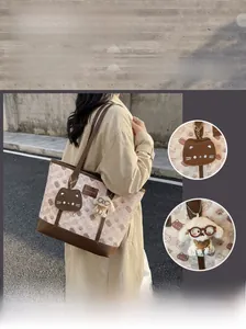 Dettaglio della borsa tote in tela con motivo gatto pane e ciondolo a forma di cane