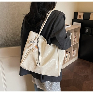 Detail of crinkled glossy tote bag in cream with a cute horse charm and shoulder straps