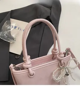 Sac seau en cuir rose avec poignée torsadée et breloque nœud en perles élégante