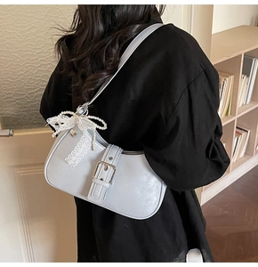 Detail of light blue crescent shoulder bag with silver buckle and pearl bow charm