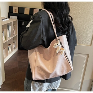 Macro detail of pink tote bag with pleated texture and white pony charm on shoulder strap