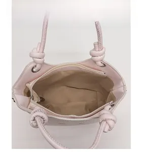 Macro view of the pink bucket bag interior with light beige lining and zipped pocket