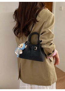 Detail of retro black crossbody bucket bag with decorative buckle and cute bear pendant