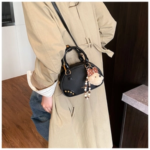 Detail of black bowling bag with golden rivets and a cute plush bear charm accessory